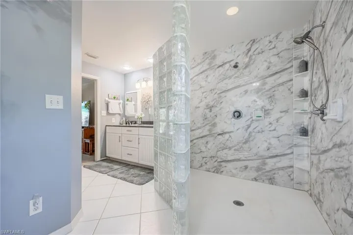 Bathroom with a marble finish shower, vanity, and tile patterned floors