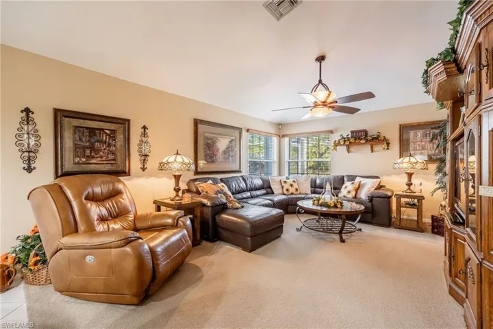 Living area with visible vents, a ceiling fan, and light colored carpet