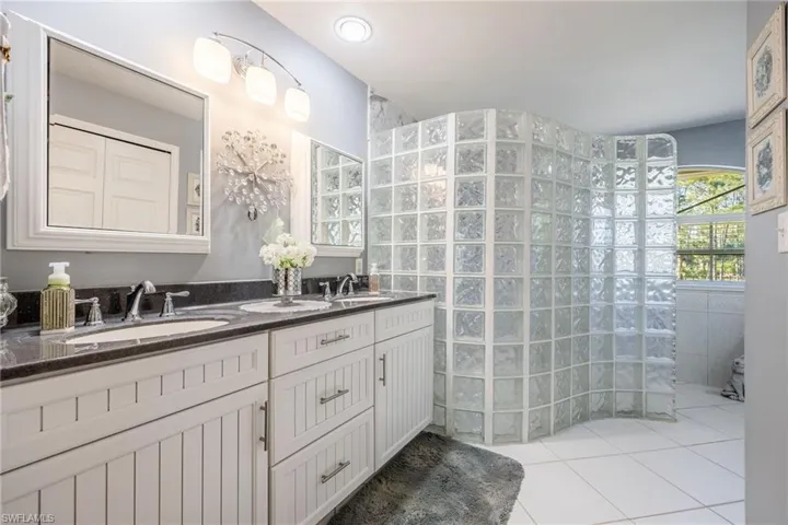 Full bathroom featuring tile patterned flooring, a walk in shower, a sink, and double vanity