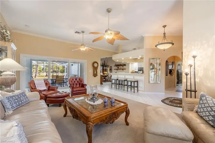Living room with visible vents, arched walkways, crown molding, and tile patterned floors