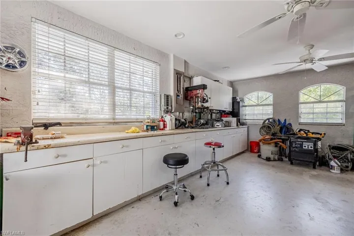 Kitchen featuring a textured wall, white cabinets, concrete flooring, and light countertops