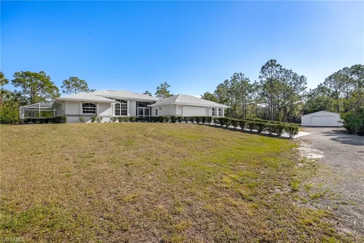 View of front of house with glass enclosure, an outdoor structure, and a front yard