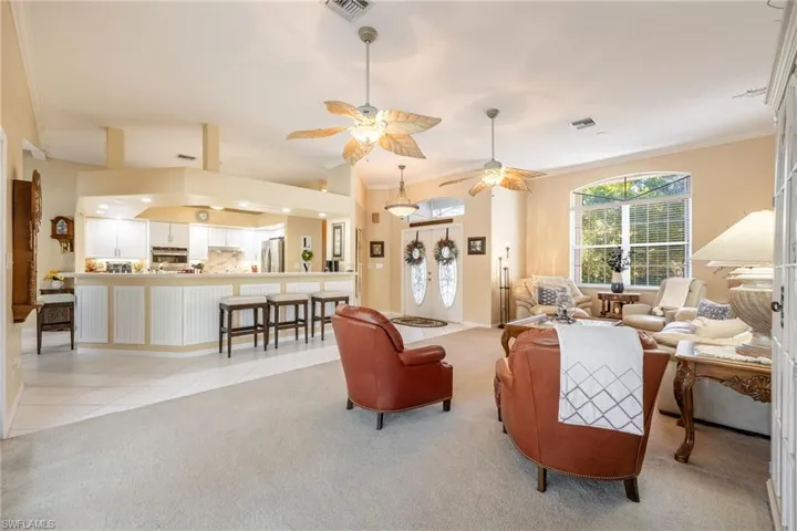 Living area featuring light carpet, light tile patterned flooring, visible vents, and crown molding