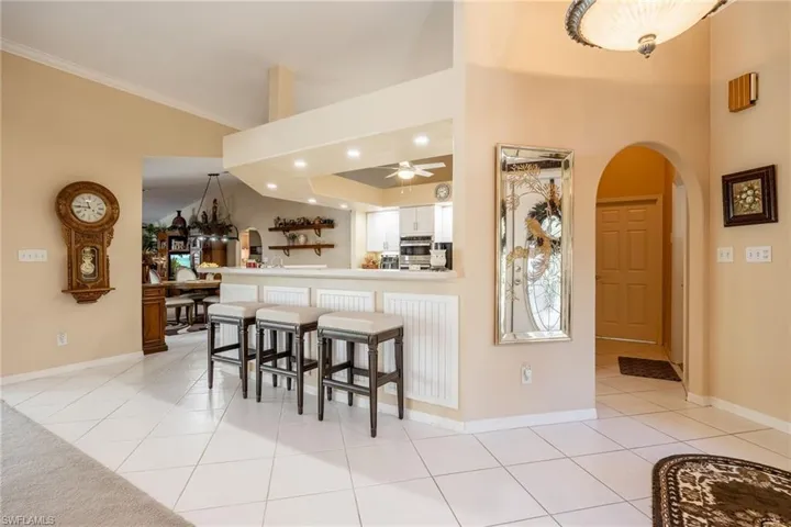 Kitchen with light tile patterned floors, white cabinetry, arched walkways, and a kitchen breakfast bar