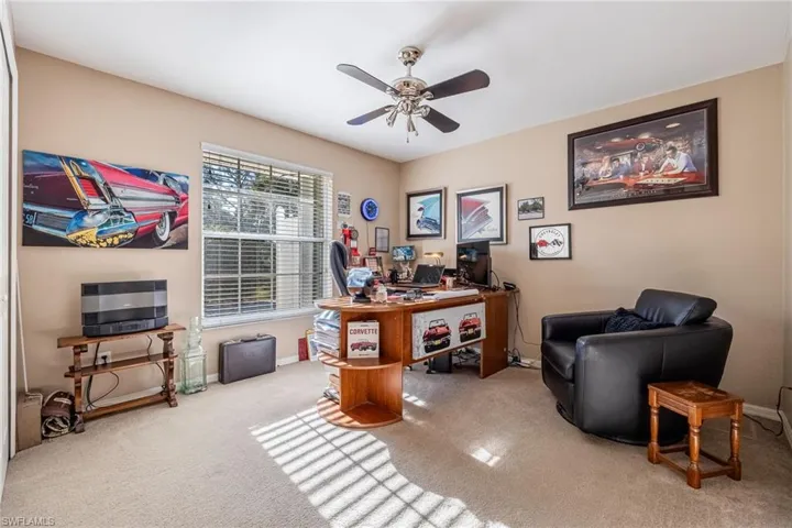 Carpeted office space with ceiling fan and baseboards