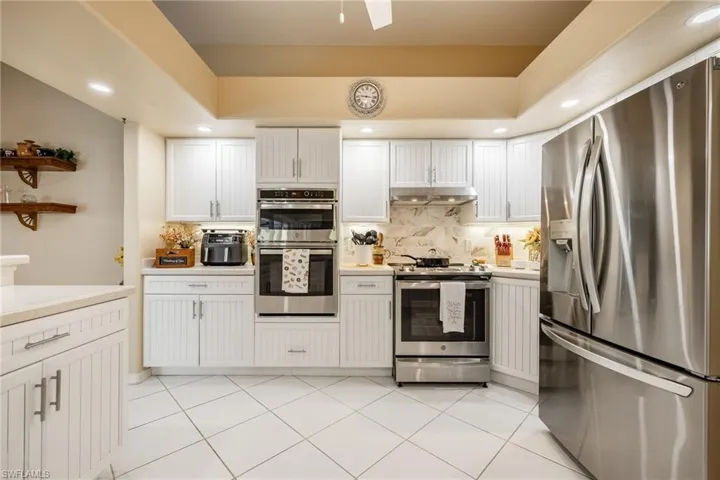 Kitchen featuring stainless steel appliances, backsplash, light countertops, and under cabinet range hood