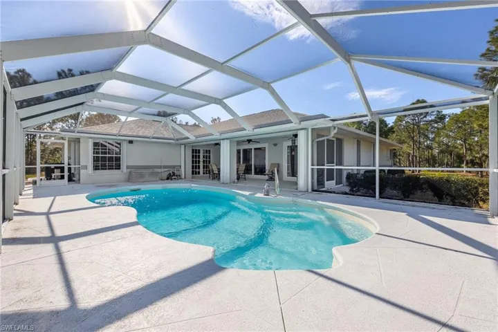 Outdoor pool featuring ceiling fan, glass enclosure, and a patio area