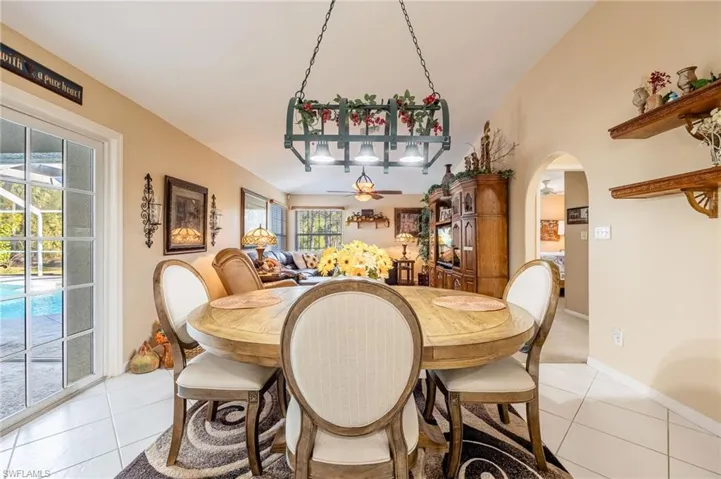 Dining area with light tile patterned floors, baseboards, arched walkways, and ceiling fan