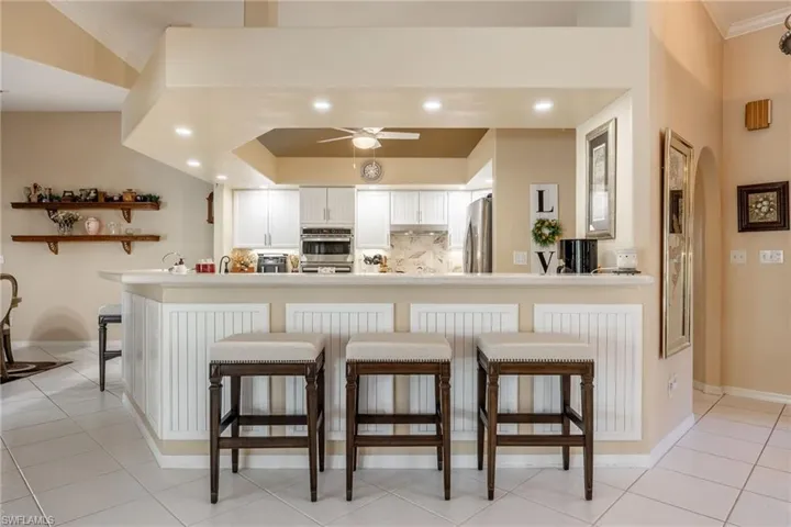 Kitchen featuring light tile patterned floors, a breakfast bar area, stainless steel appliances, a peninsula, and decorative backsplash