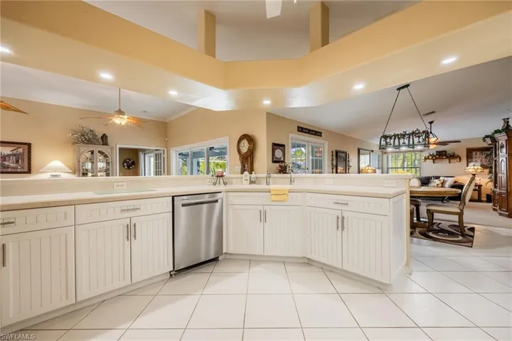 Kitchen featuring light tile patterned floors, dishwasher, open floor plan, hanging light fixtures, and light countertops