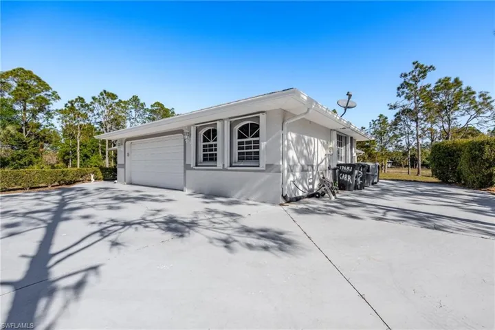 View of side of home with concrete driveway, an attached garage, and stucco siding