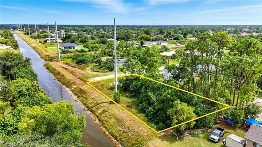 Aerial perspective of suburban area with property parcel outlined and a large body of water