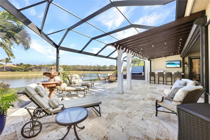 Lanai with premium water view, panoramic screened enclosure, pergola, built-in hot tub, outdoor kitchen, bar and covered living area