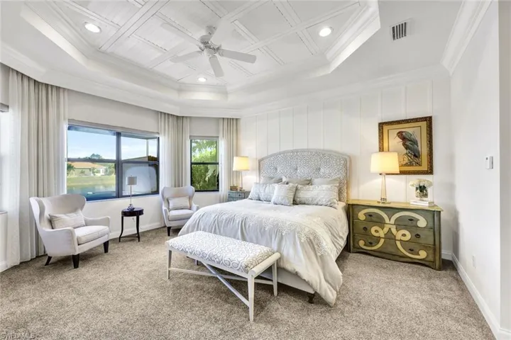 Primary bedroom with a tray ceiling, new carpet, custom window treatments, new carpet, access to exterior, ceiling fan, and extensive molding & trim