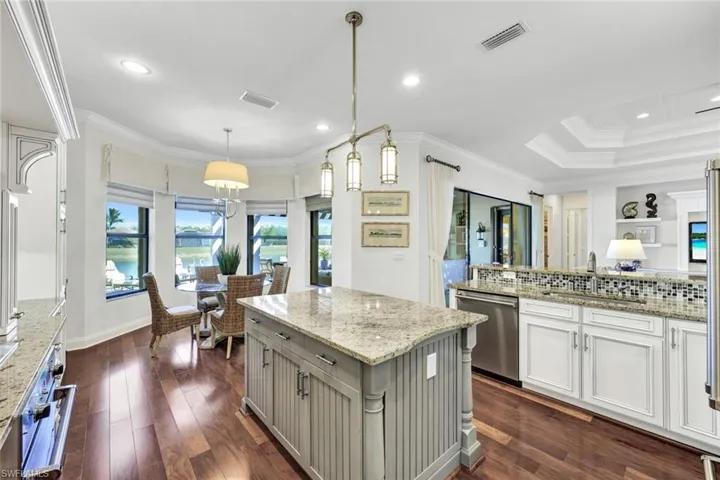 Kitchen with backsplash, hardwood floors, light stone countertops, custom window treatments, decorative light fixtures, and Viking appliances