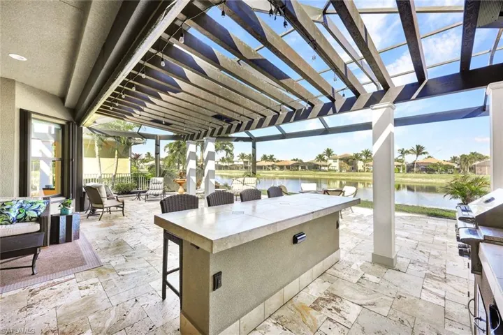 Lanai with premium water view, panoramic screened enclosure, pergola, built-in hot tub, outdoor kitchen, bar and covered living area