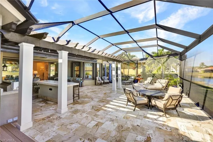 Lanai with premium water view, panoramic screened enclosure, pergola, built-in hot tub, outdoor kitchen, bar and covered living area