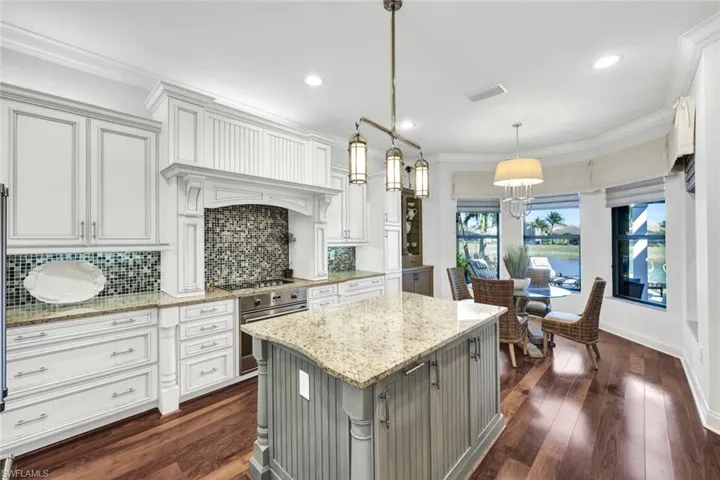 Kitchen with backsplash, hardwood floors, light stone countertops, custom window treatments, decorative light fixtures, and Viking appliances