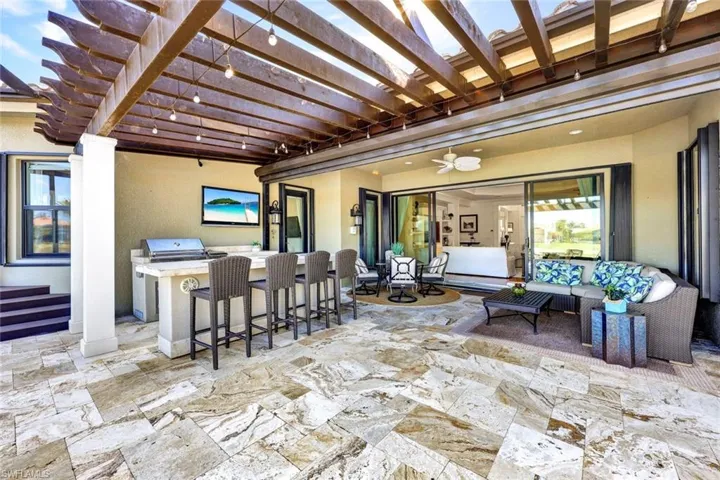 Lanai with premium water view, panoramic screened enclosure, pergola, built-in hot tub, outdoor kitchen, bar and covered living area