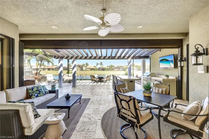 Lanai with premium water view, panoramic screened enclosure, pergola, built-in hot tub, outdoor kitchen, bar and covered living area