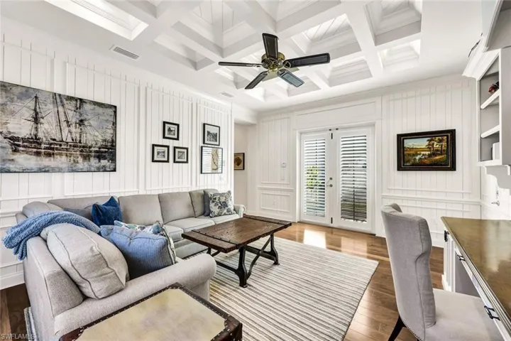 Den with designer furnishings, ceiling fan, coffered ceiling, hardwood floors, crown molding, built in desk and shelving