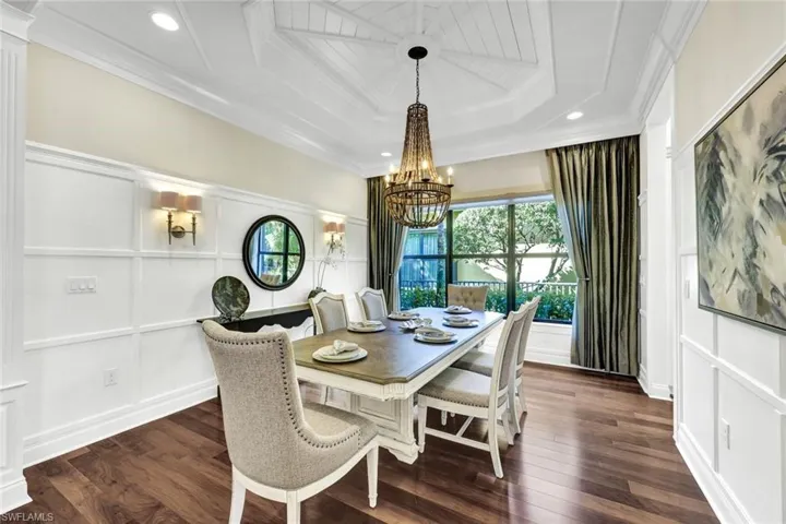 Dining room with designer furnishings, hardwood flooring, an inviting chandelier, and extensive molding & trim