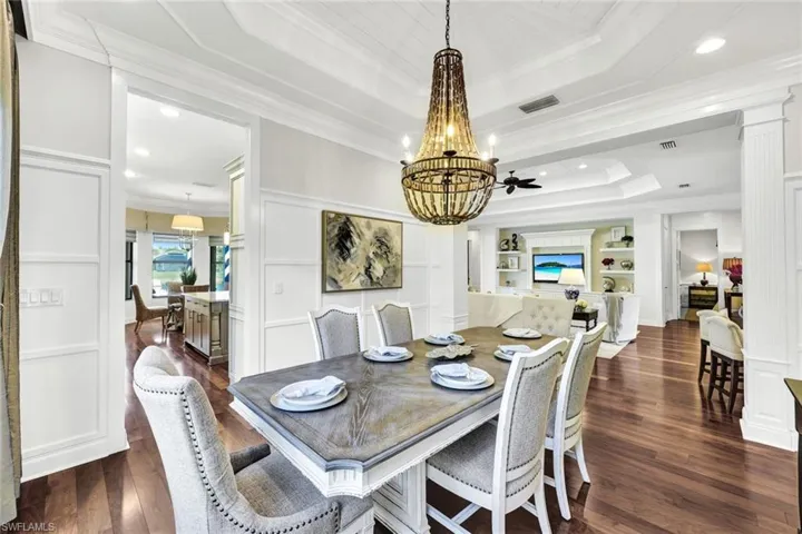 Dining room with designer furnishings, hardwood flooring, an inviting chandelier, and extensive molding & trim