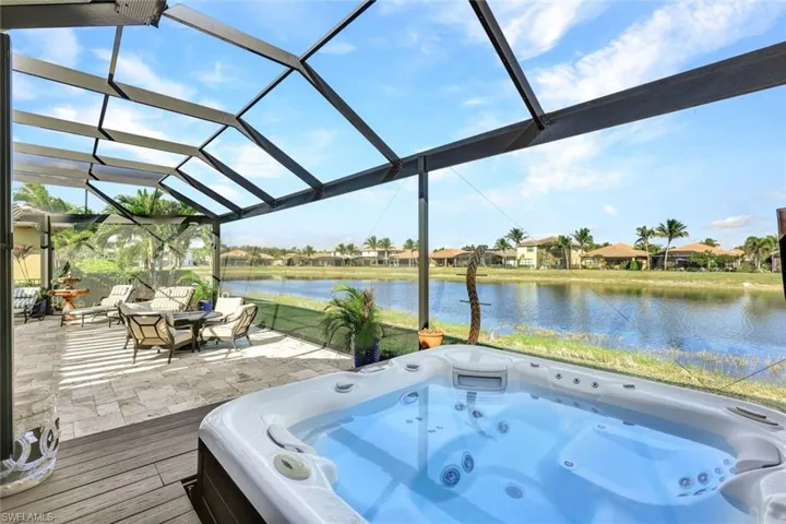 Lanai with premium water view, panoramic screened enclosure, pergola, built-in hot tub, outdoor kitchen, bar and covered living area