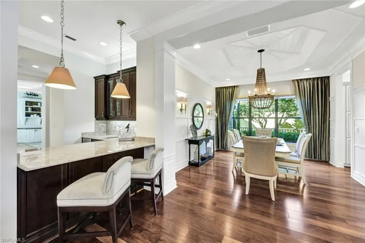 Dining room with designer furnishings, hardwood flooring, an inviting chandelier, and extensive molding & trim