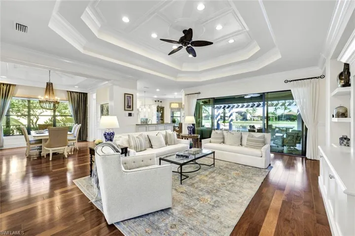 Living room featuring designer furnishings, built in shelves/cabinets, hardwood flooring, a tray ceiling, and crown molding