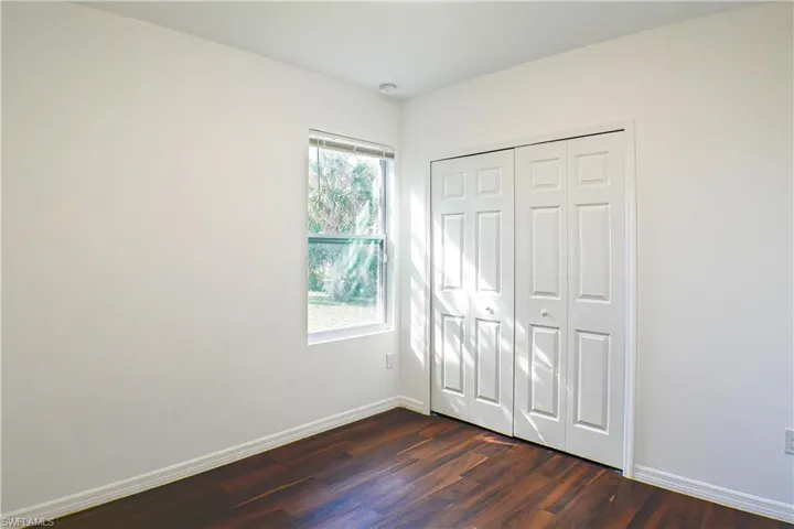 Unfurnished bedroom featuring dark wood-style flooring and a closet