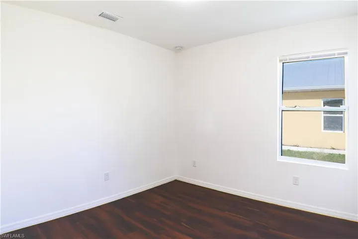Unfurnished room featuring baseboards and dark wood-style flooring