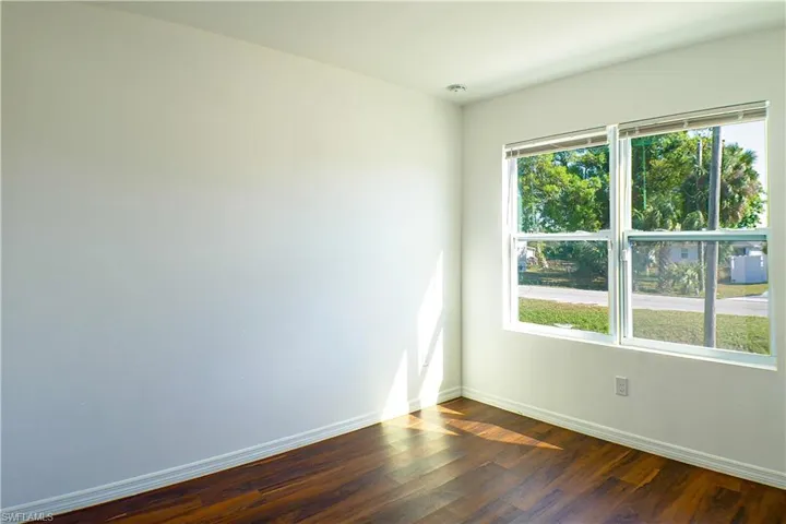 Empty room with baseboards and dark wood-style flooring