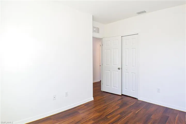 Unfurnished bedroom with dark wood-type flooring and a closet