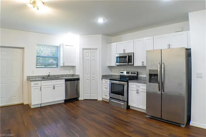 Kitchen featuring appliances with stainless steel finishes, white cabinetry, light stone counters, and recessed lighting