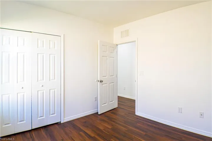 Unfurnished bedroom featuring dark wood-style floors and a closet