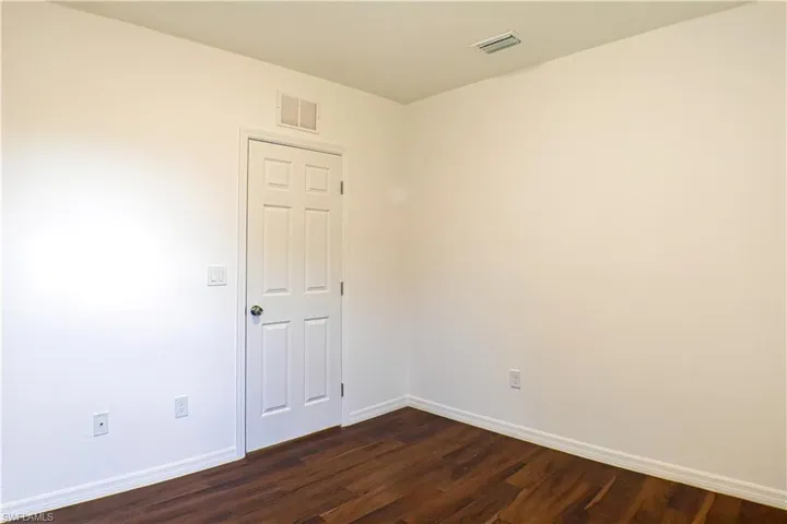 Empty room with dark wood finished floors and baseboards