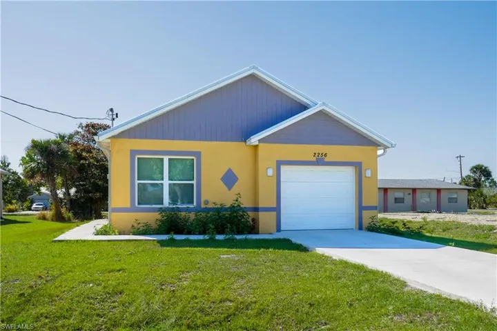View of front of property with a front lawn, an attached garage, stucco siding, and concrete driveway