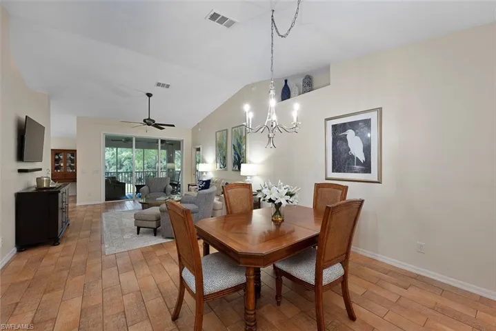 Dining room featuring a chandelier, vaulted ceiling, light wood-style floors, and ceiling fan