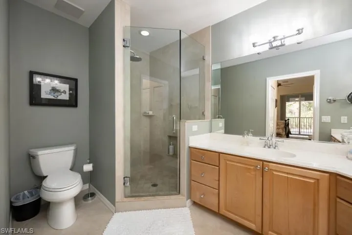 Full bath with a stall shower, vanity, light tile patterned floors, and a ceiling fan