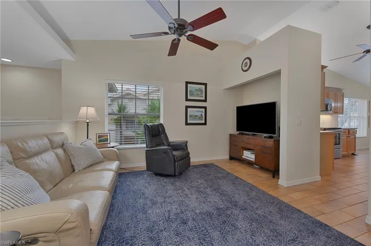 Living area featuring lofted ceiling, ceiling fan, and light wood-type flooring