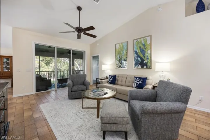 Living room with light wood-style floors, high vaulted ceiling, and a ceiling fan