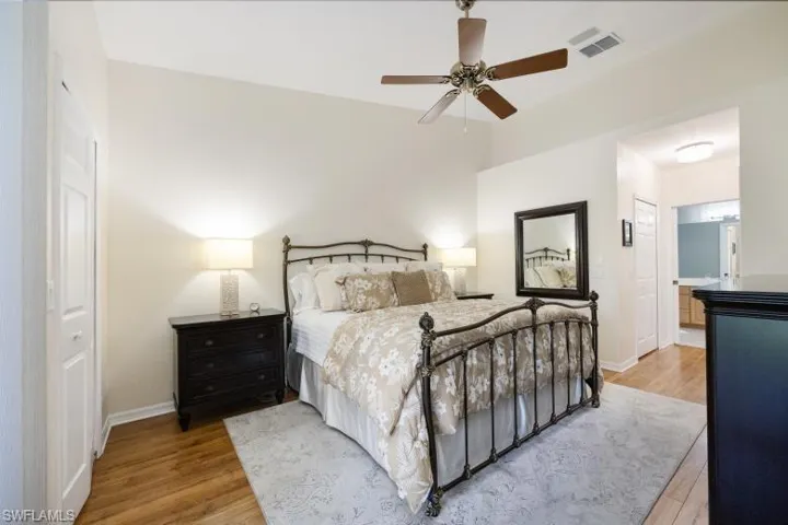 Bedroom with light wood-type flooring, ceiling fan, and ensuite bath