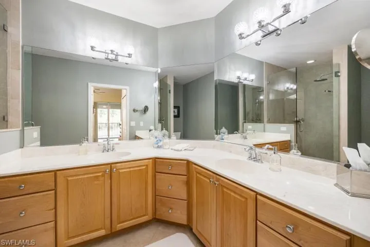 Bathroom featuring double vanity, a shower stall, and light tile patterned flooring