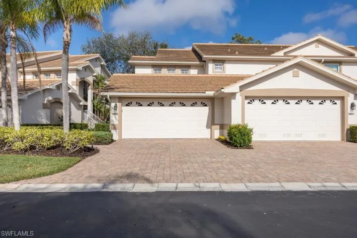 Traditional-style home featuring stucco siding, a tiled roof, decorative driveway, and a garage