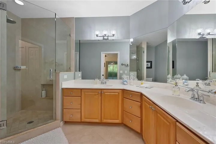 Full bath featuring a stall shower, light tile patterned floors, and double vanity