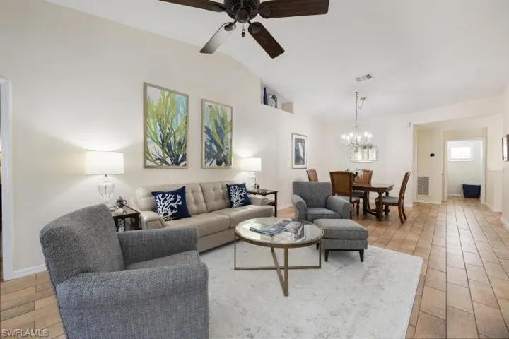 Living area featuring lofted ceiling, light wood-style flooring, a ceiling fan, and a chandelier