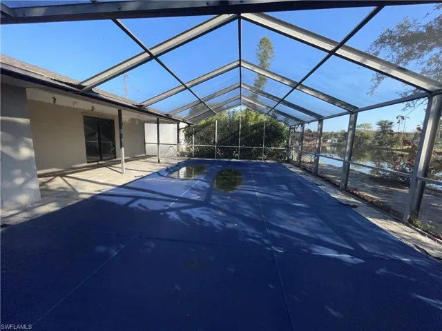 Swimming pool featuring a screened lanai, a water view, and a patio area
