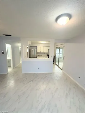 Unfurnished living room with a textured ceiling and light tile patterned floors