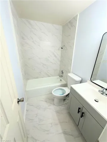 Full bathroom with tiled shower / bath, toilet, tile patterned floors, and vanity